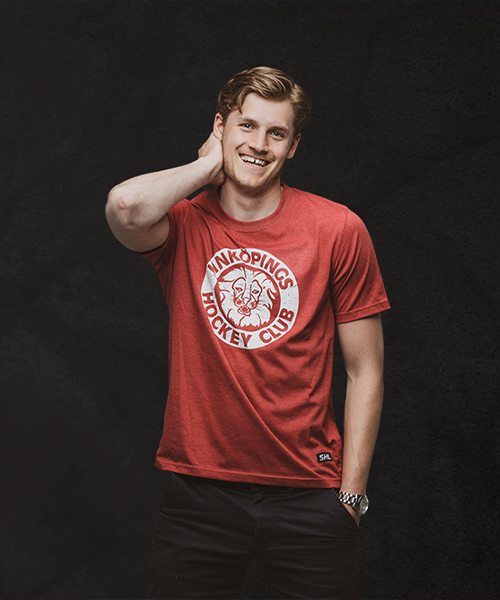 Känd svensk hockeyspelare poserar med sin klubbtröja.